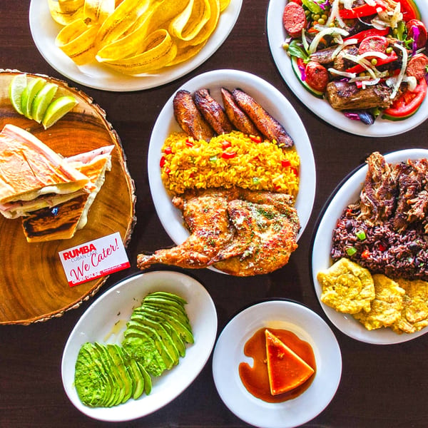 A spread of Cuban dishes including roasted chicken, rice, plantains, salad, and flan.