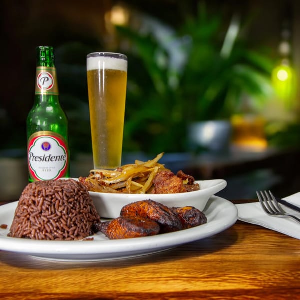 Cuban meal with rice, plantains, fried meat with onions, and a Presidente beer.