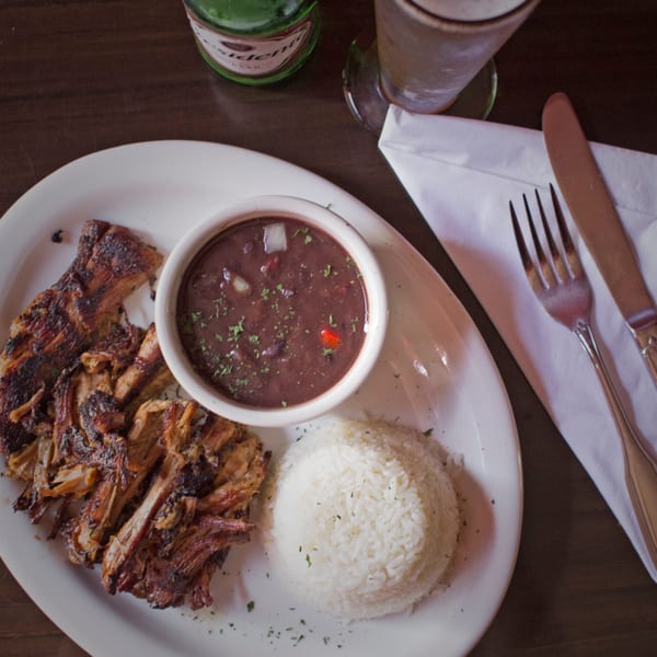 Rumba Cuban Cafe's roasted pork with black beans and white rice, a beer bottle and glass.