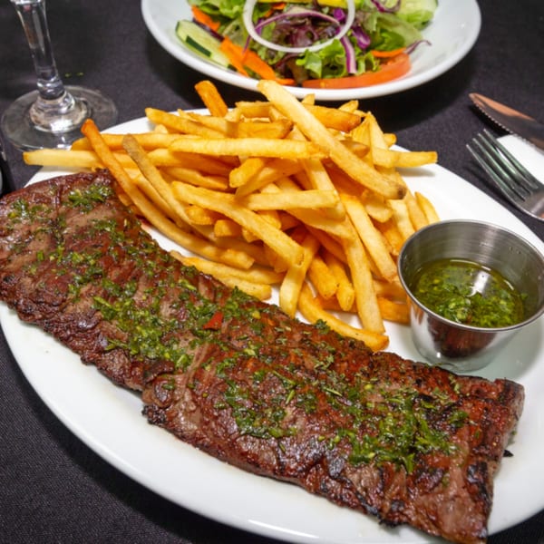 Grilled Cuban skirt steak with chimichurri, a side of golden french fries, and a fresh salad.