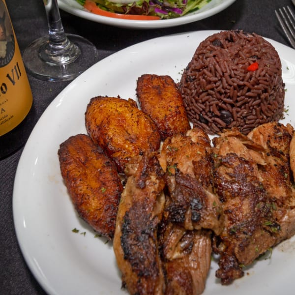 Rumba Cuban Cafe's roasted pork, fried plantains, and black bean rice on a white plate.