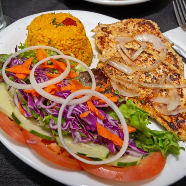 Rumba Cuban Cafe's grilled chicken with onions, yellow rice, and a fresh garden salad.