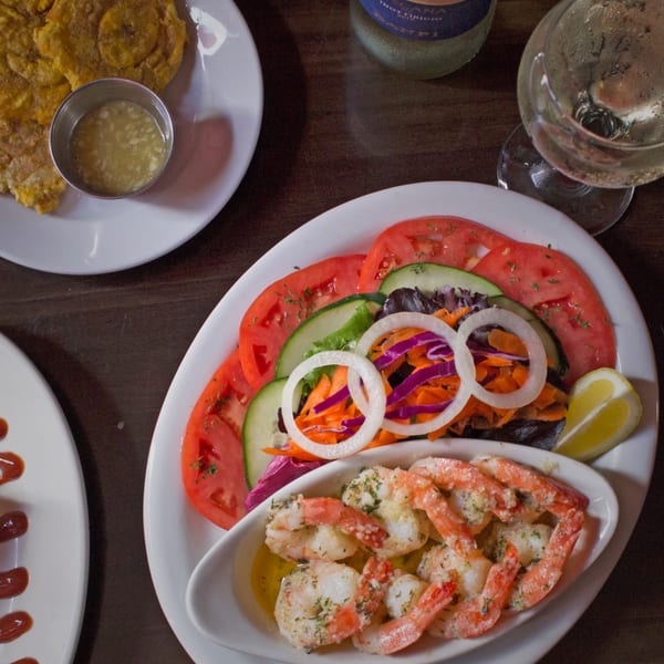 Cuban garlic shrimp with a side salad, tostones, and a glass of white wine.