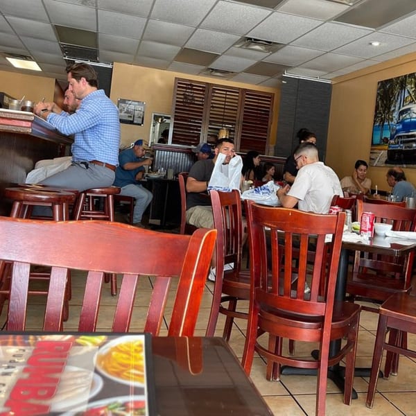 Diners enjoying meals and drinks at tables and a bar inside Rumba Cuban Cafe.