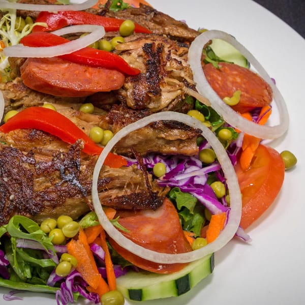 Rumba Cuban Cafe's roasted pork with red peppers, onions, chorizo, and green peas over a fresh salad.